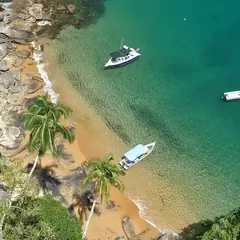 Praia com coqueiros e lanchas ancoradas