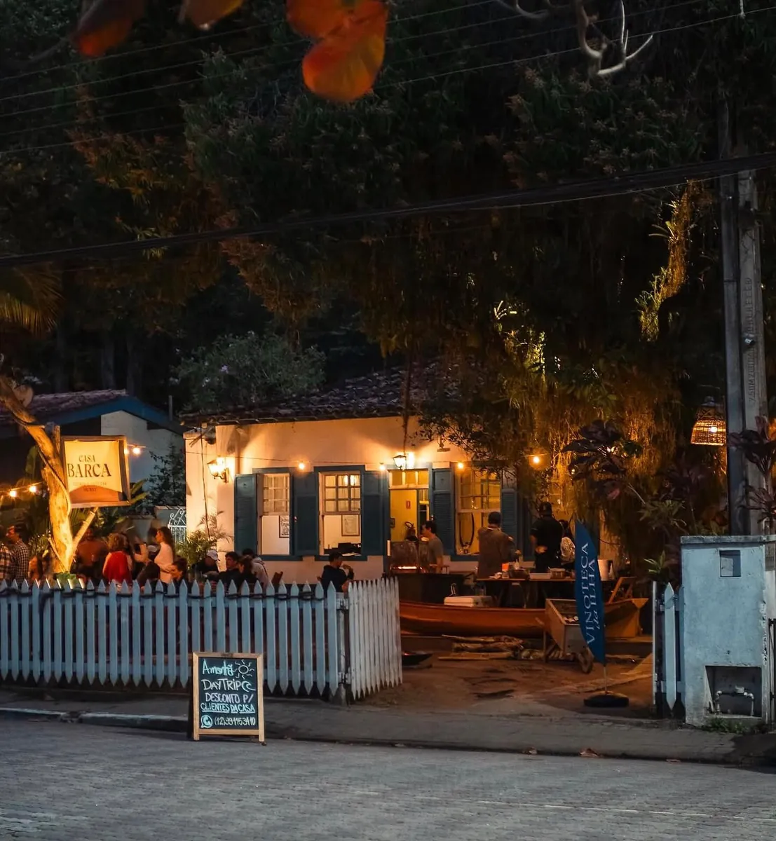 Fachada da Casa Barca à noite, com cerca branca e luzes