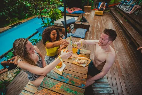 Amigos brindando no deck de madeira ao lado da piscina