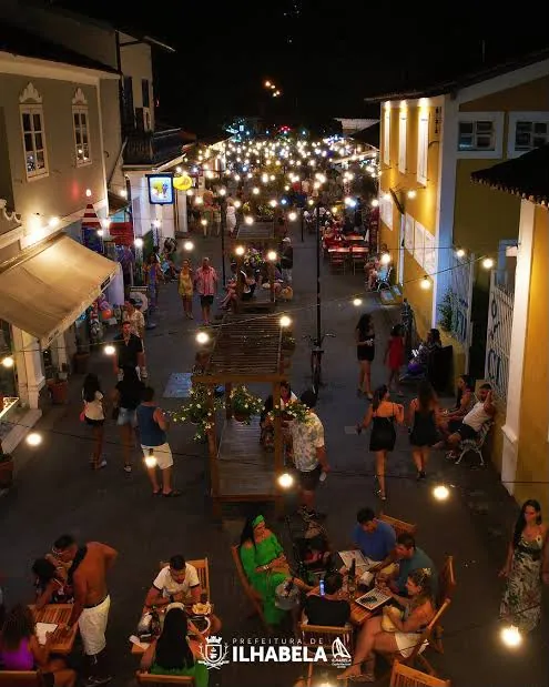 Vista do alto da Rua do Meio iluminada, com mesas e pessoas à noite
