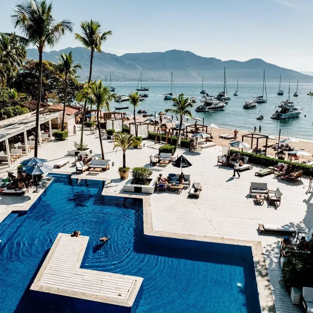 Piscina e espreguiçadeiras do Sea Club de frente para a praia e os barcos
