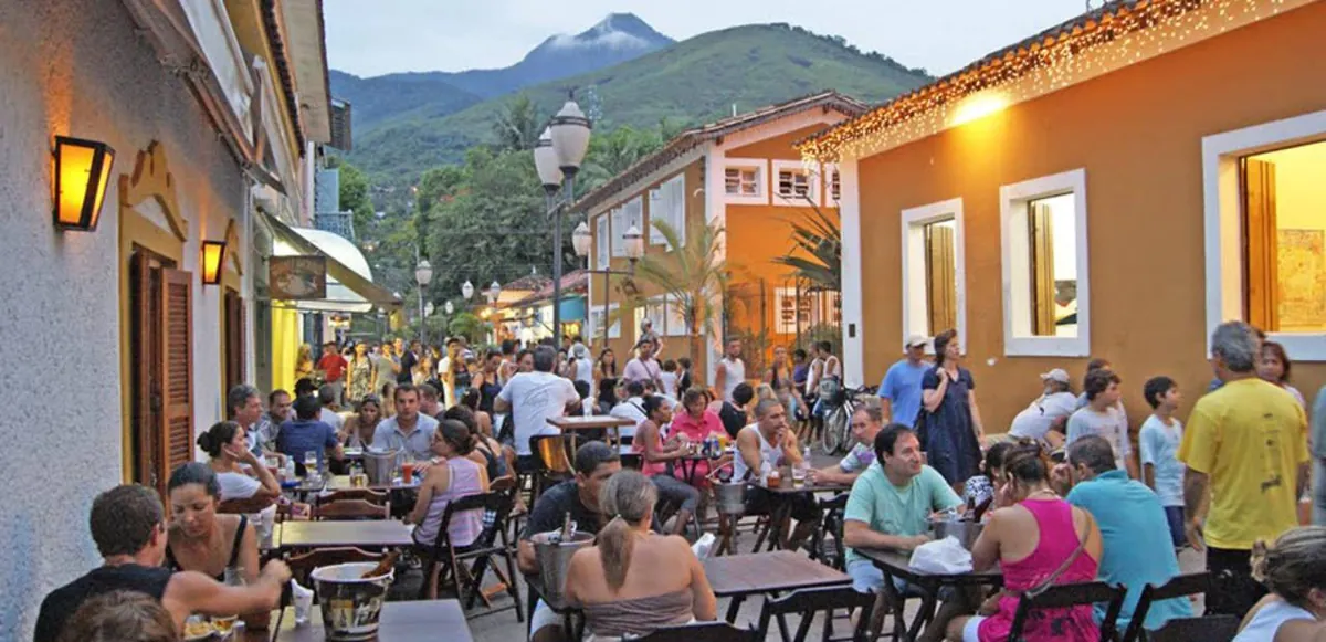 Movimento noturno nas ruas da Vila, com o Pico do Baepi ao fundo