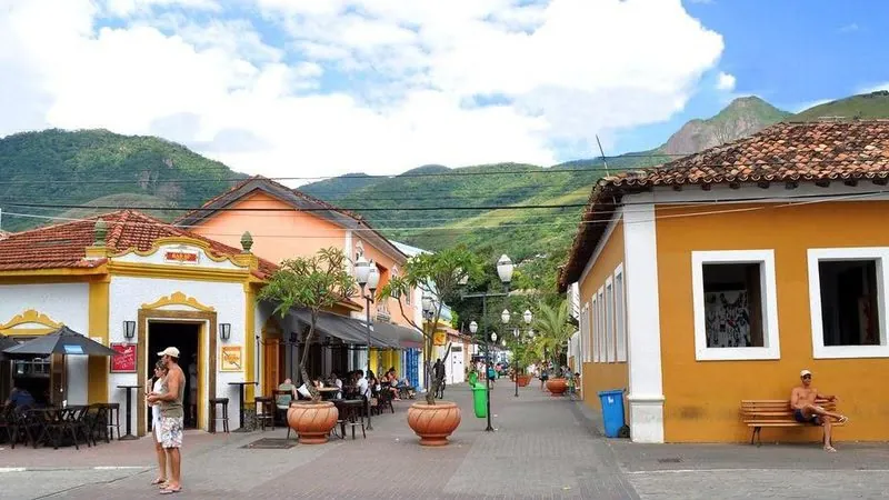 Rua do Centro Histórico da Vila com casarões coloridos e a serra ao fundo