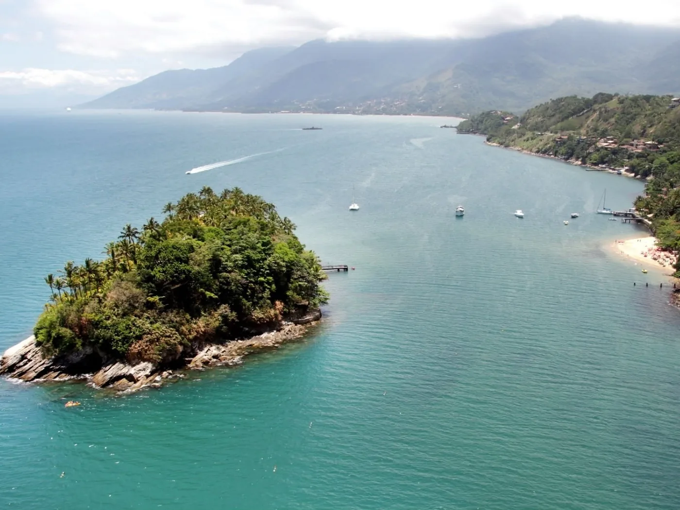 Vista aérea da Ilha das Cabras, com águas verdes e a praia ao lado, em Ilhabela