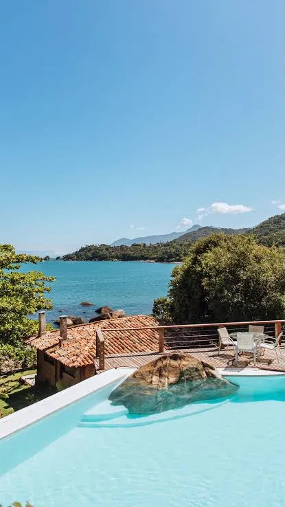 Piscina com deck e vista para o costão e o mar, em casa da BNB Guests