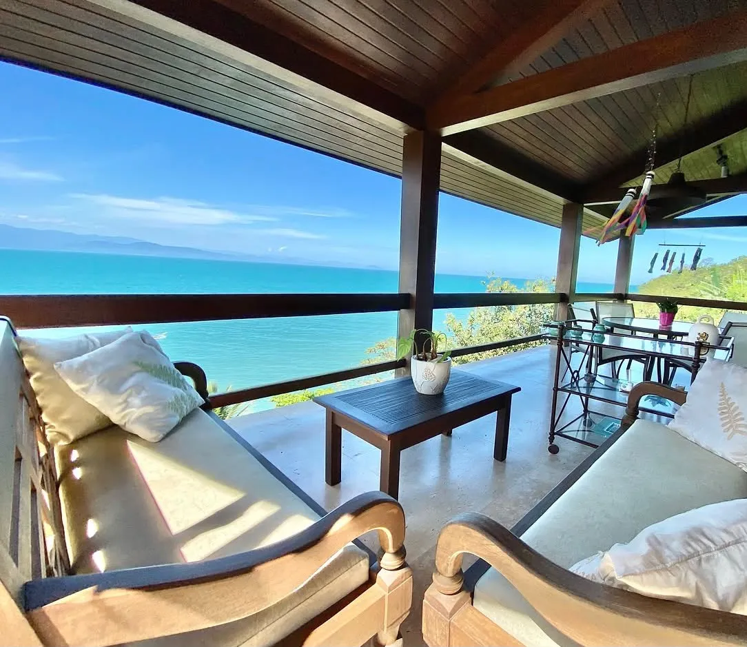 Varanda coberta com sofás e vista para o mar, em casa da BNB Guests