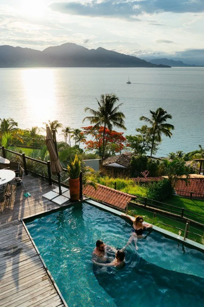 Piscina com vista para o mar e o canal de Ilhabela ao entardecer