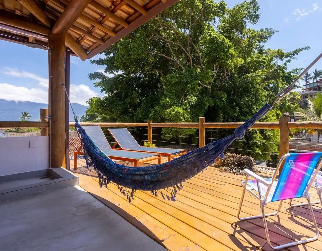 Deck de madeira com rede e espreguiçadeiras, na Casa Maembippe