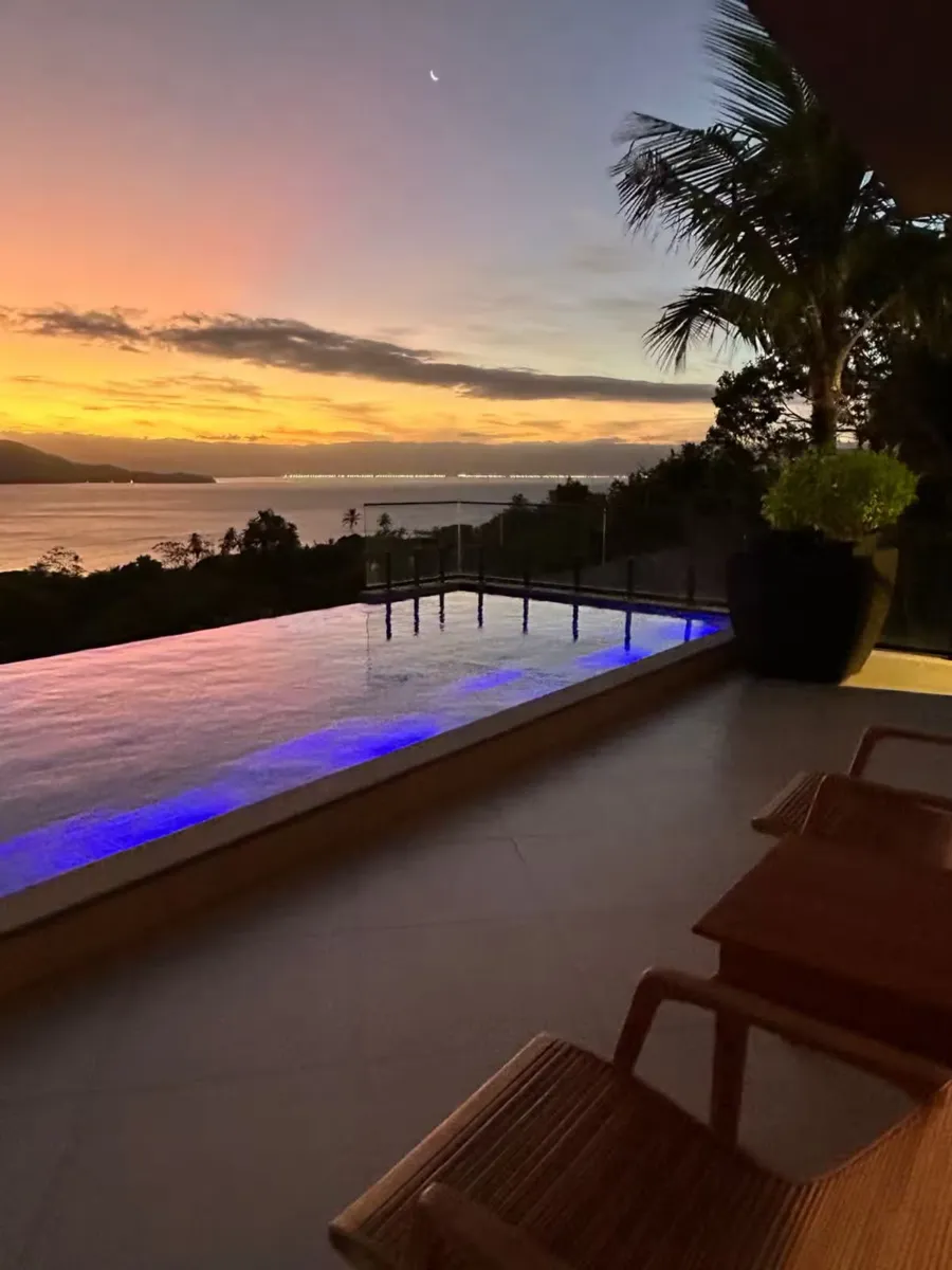 Piscina iluminada ao pôr do sol, de frente para o canal, na Maluhia