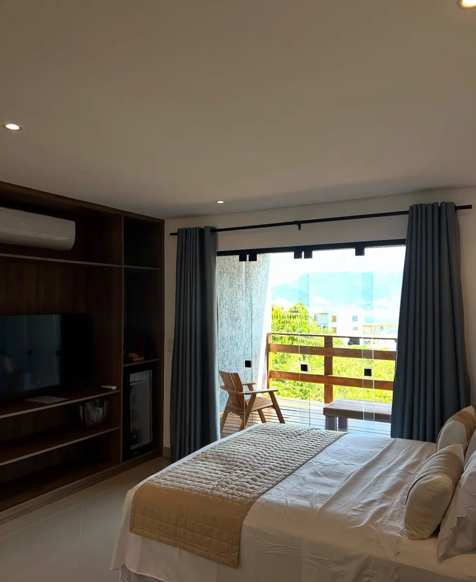 Suíte com cama de casal, TV e varanda, na Maluhia
