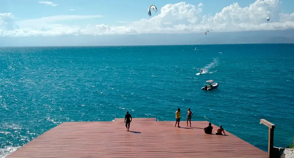 Deck de madeira da Ponta das Canas de frente para o mar, com pipas de kitesurf no céu