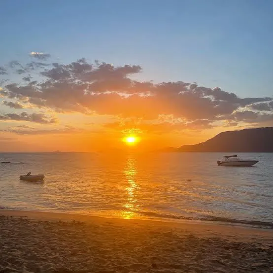 Pôr do sol sobre o canal visto da Praia do Curral, com barcos ancorados