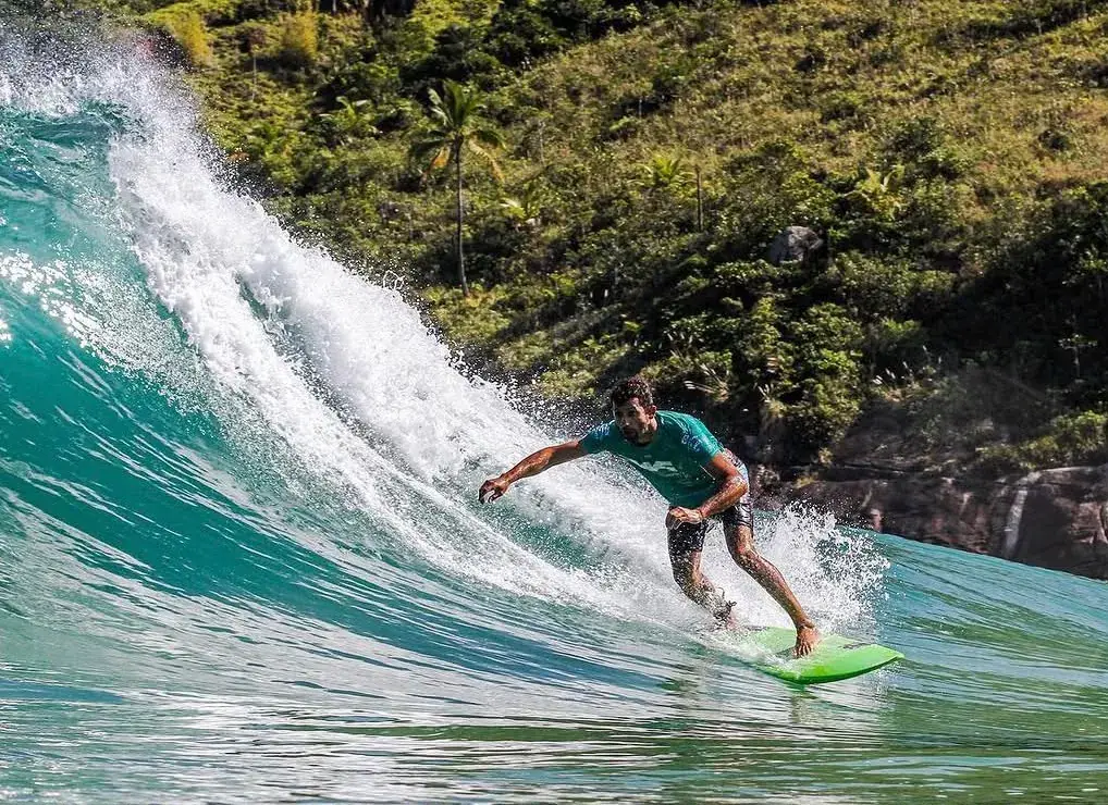Surfista fazendo manobra com prancha verde no Bonete