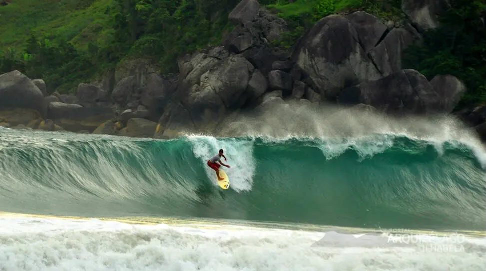 Surfista dentro de uma onda tubular junto às pedras do Bonete
