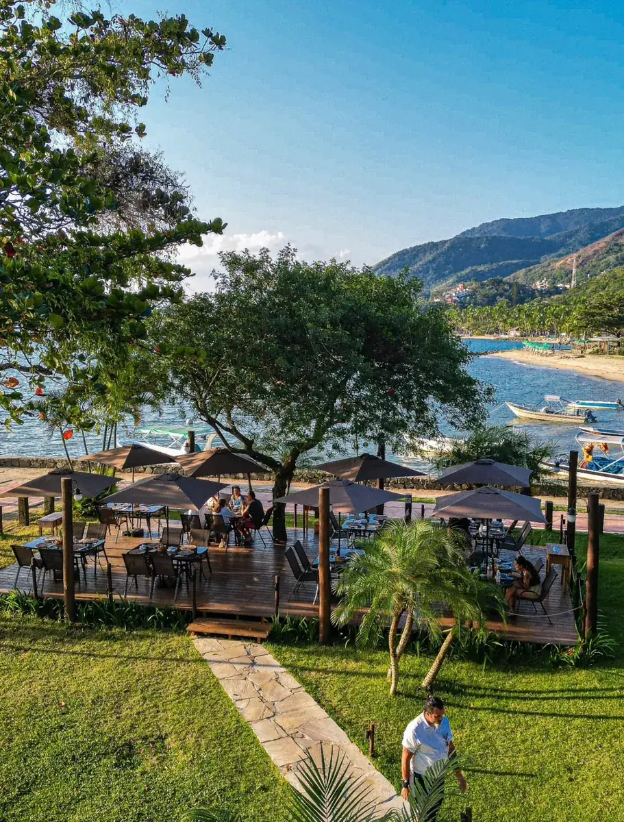 Deck do Convés Ilhabela à beira-mar no Perequê, com guarda-sóis e jardim
